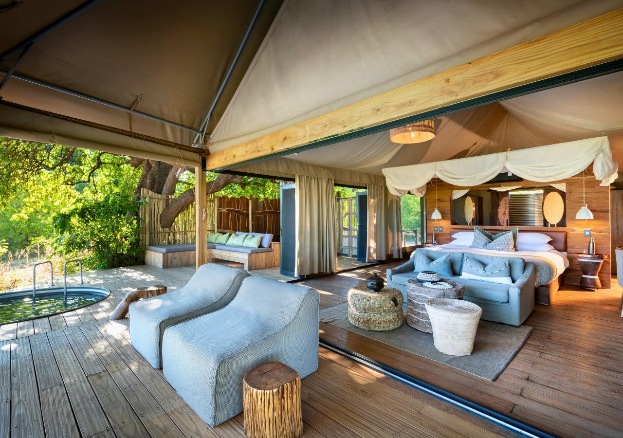 open plan bedroom and deck with a pool at a safari lodge