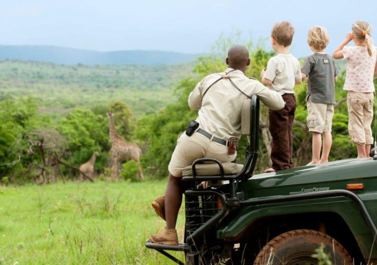 Children on a safari vehicle observing a nearby giraffe