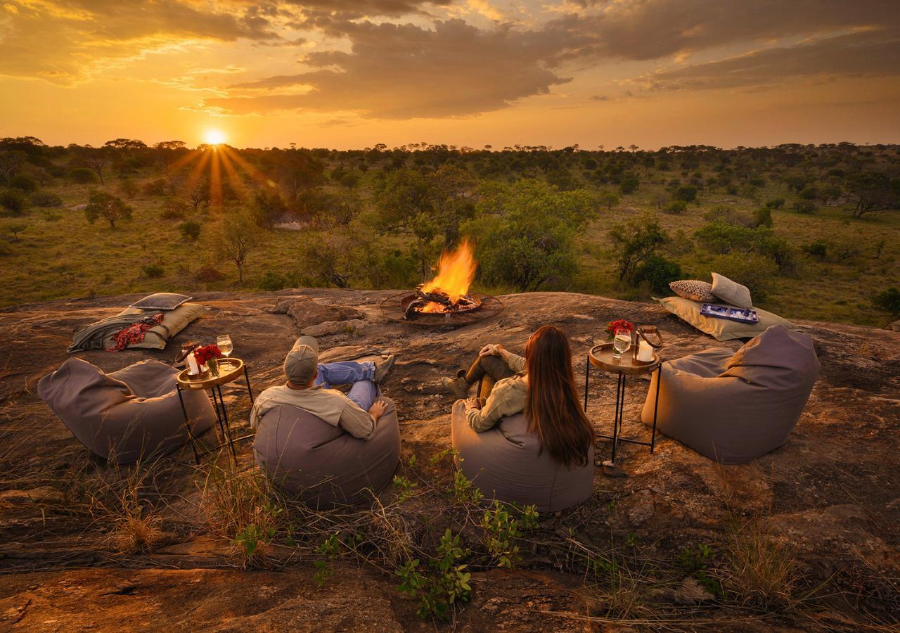 couple sitting on bean bags around a fire at sunset on safari in Tanzania