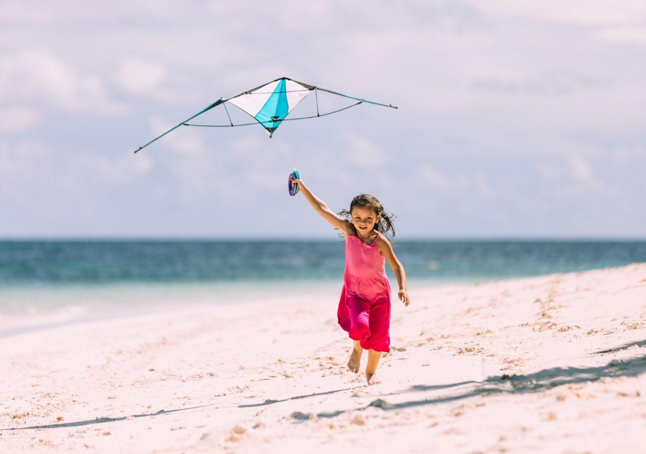 Child flying kite on beach at Four Seasons Resort Seychelles at Desroches Island