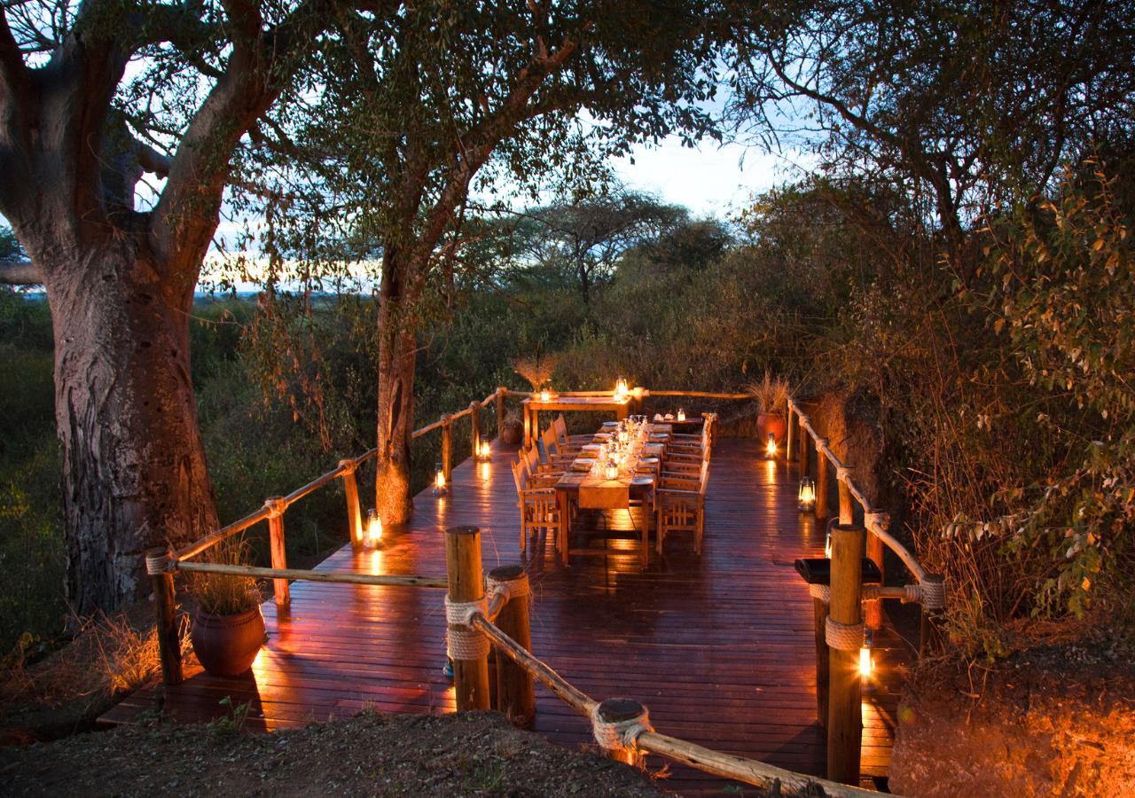 lantern lit deck with a dinner table under trees