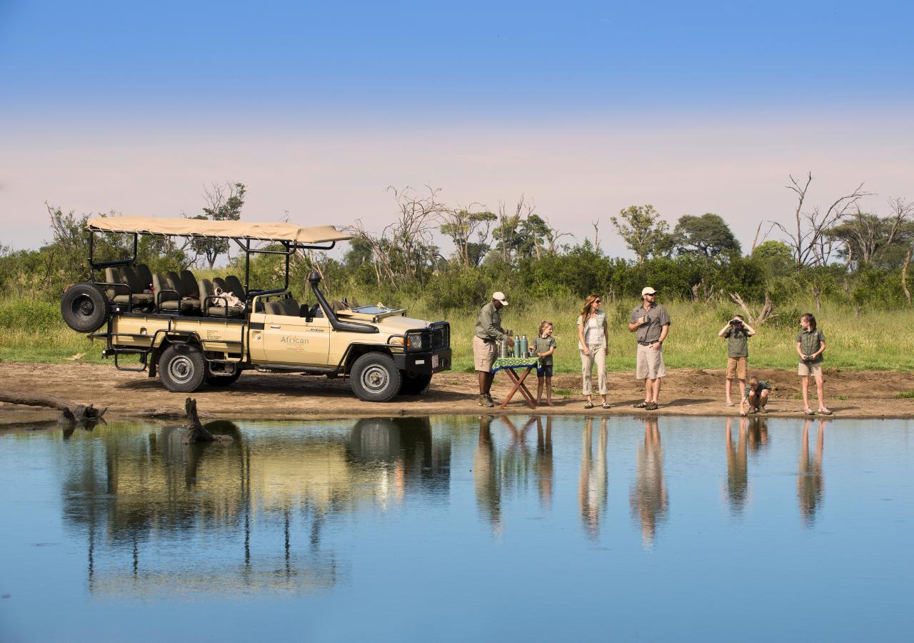 family on safari stopping next to a river for snacks and drinks