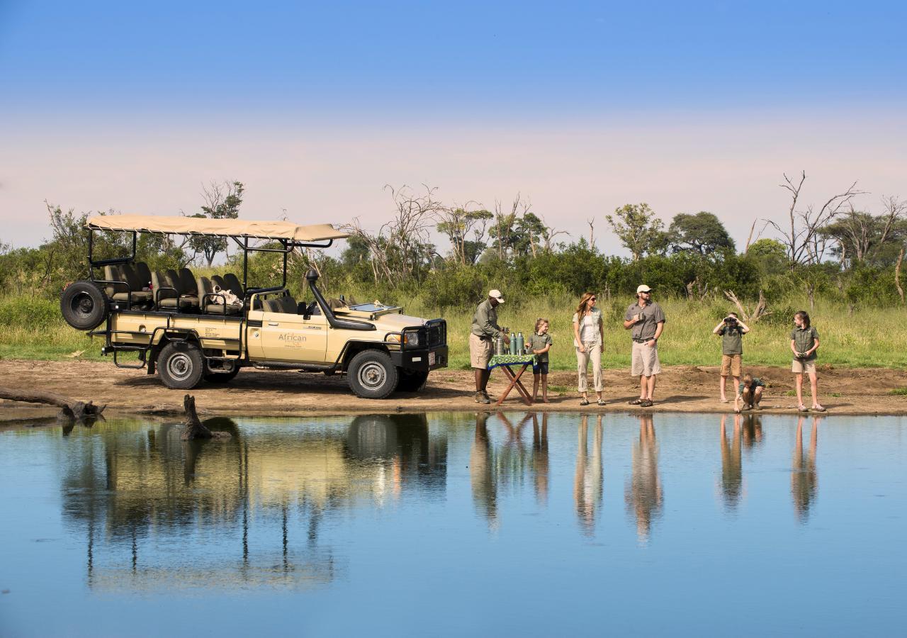 family on safari stopping along a river for drinks