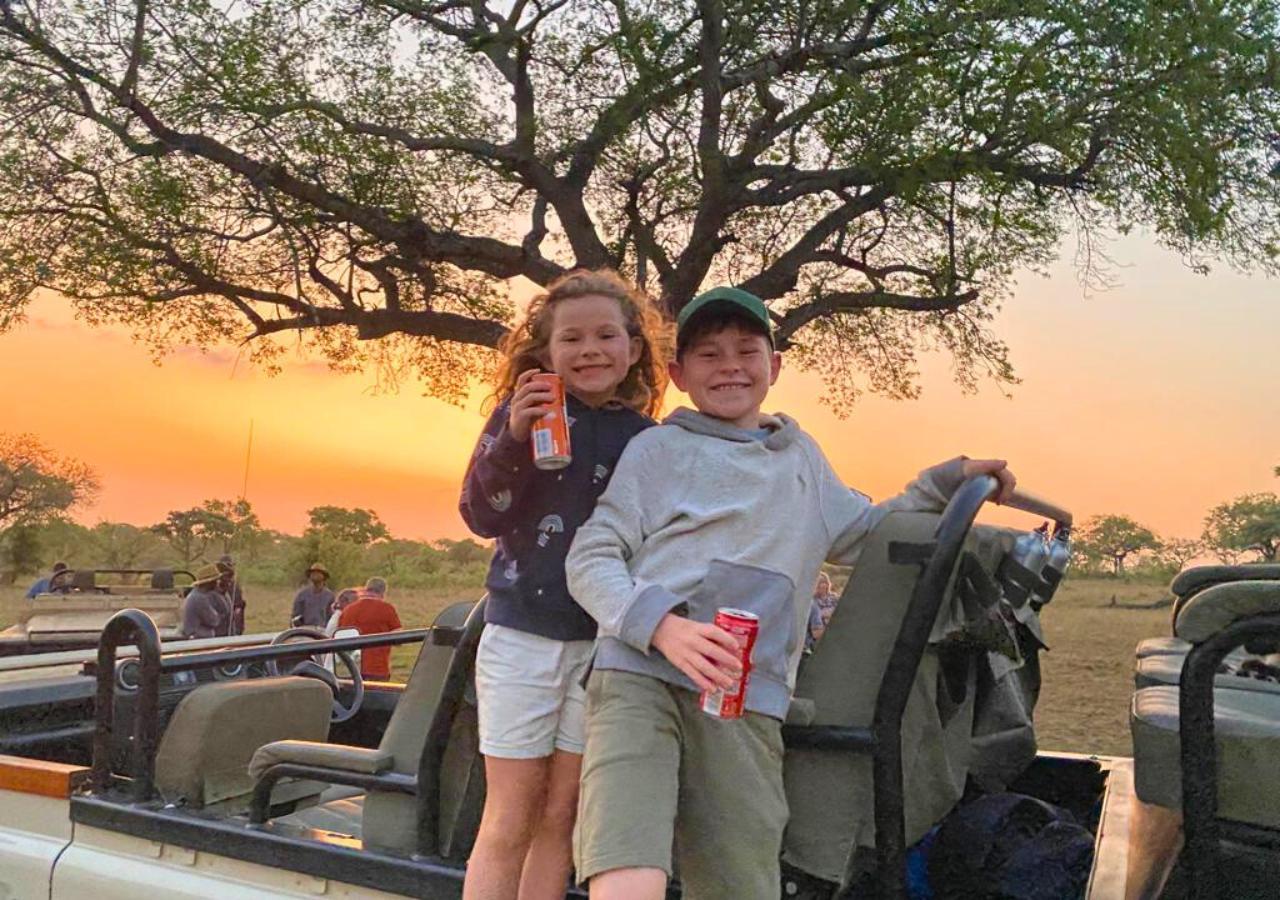 two kids standing in a safari vehicle with drinks in their hands