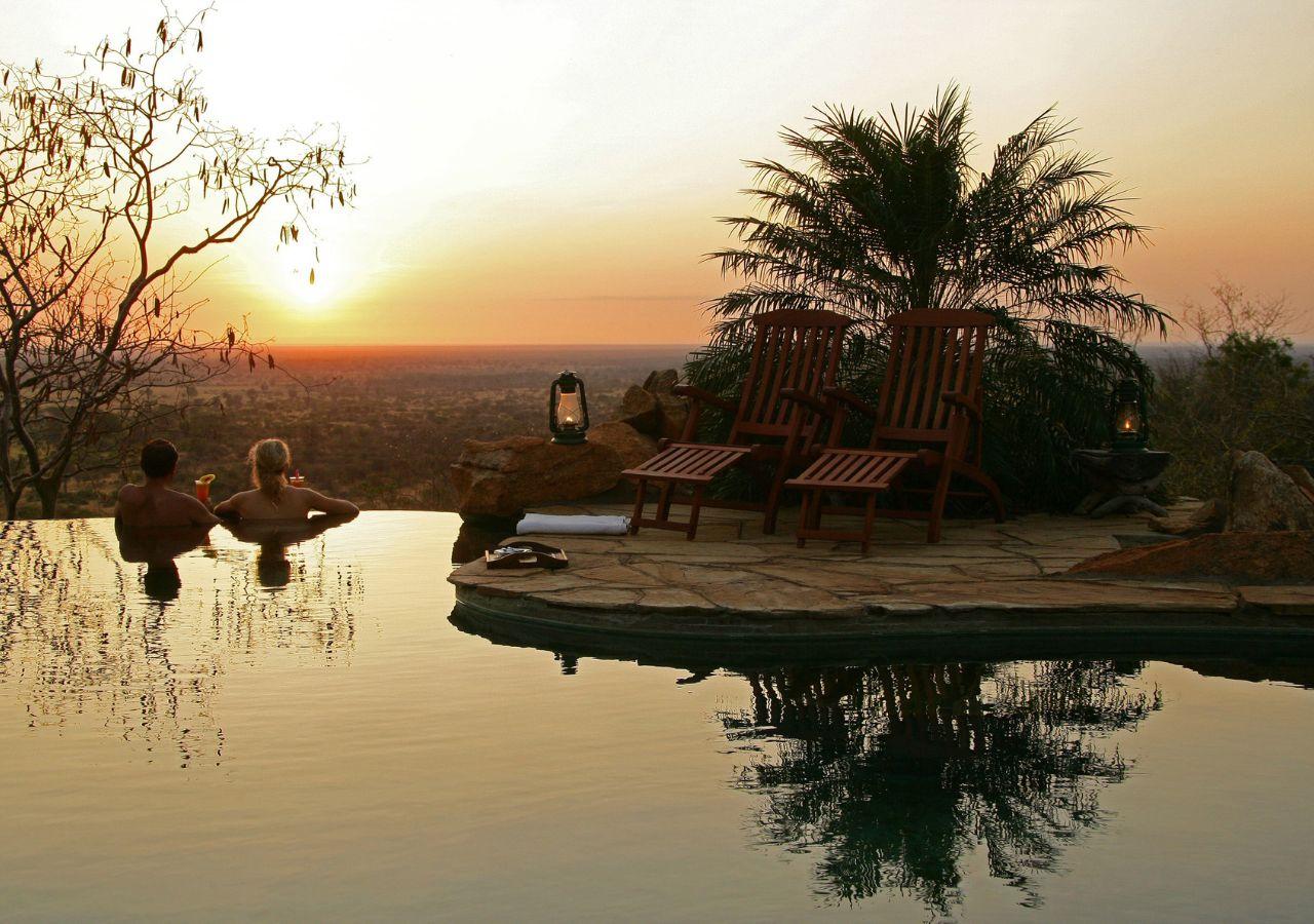 Couple with sunset drinks at the pool on safari in Kenya
