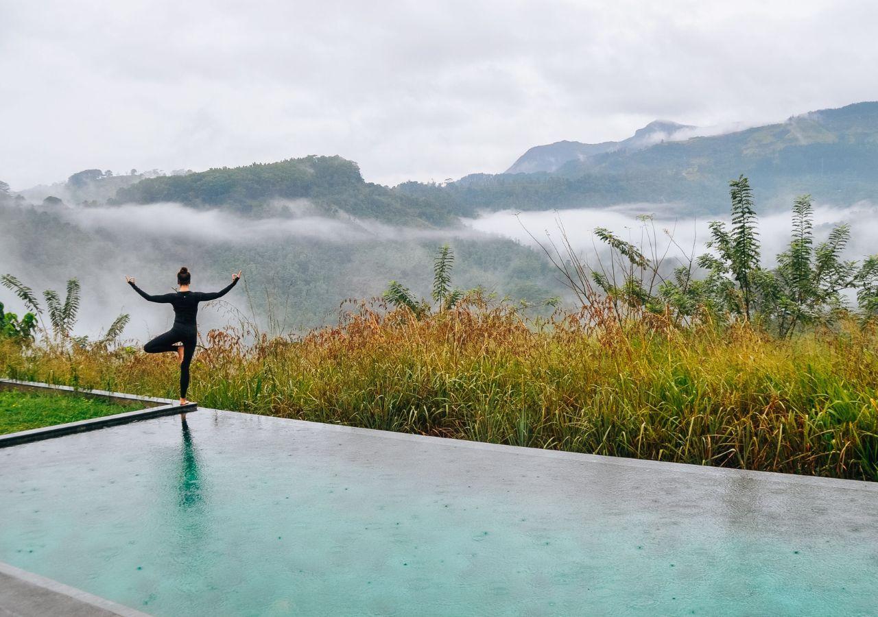 person doing yoga next to a pool at Santani Wellness Resort