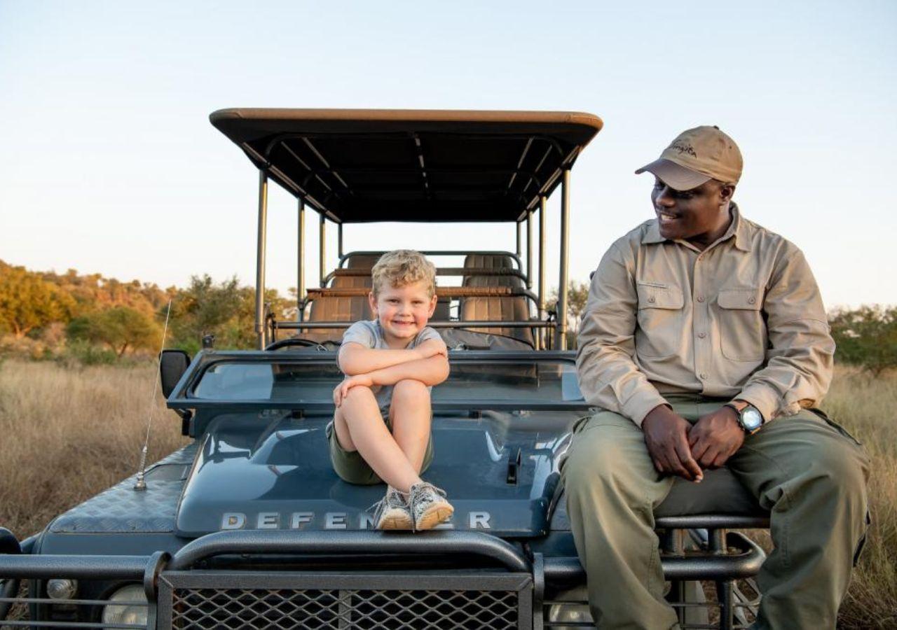 Child and safari guide sitting on a safari vehicle
