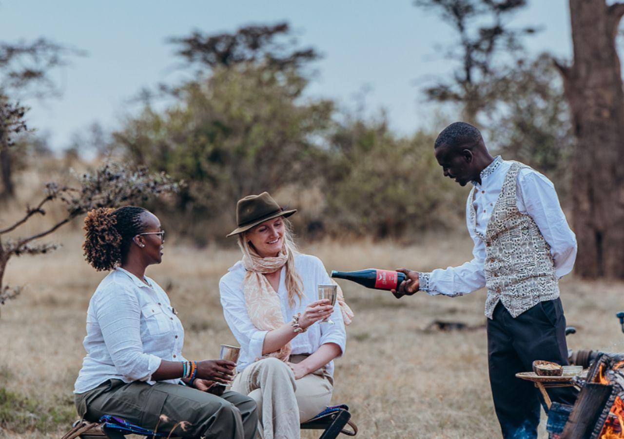 Two women have champagne poured while on safari