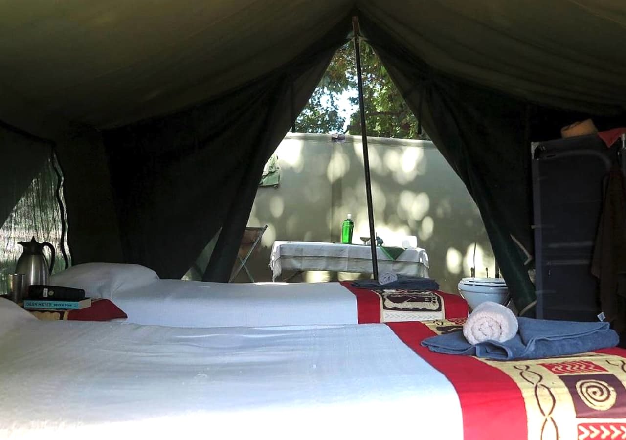 A Mana River Camp Tented Bedroom With An Outdoor Bathroom