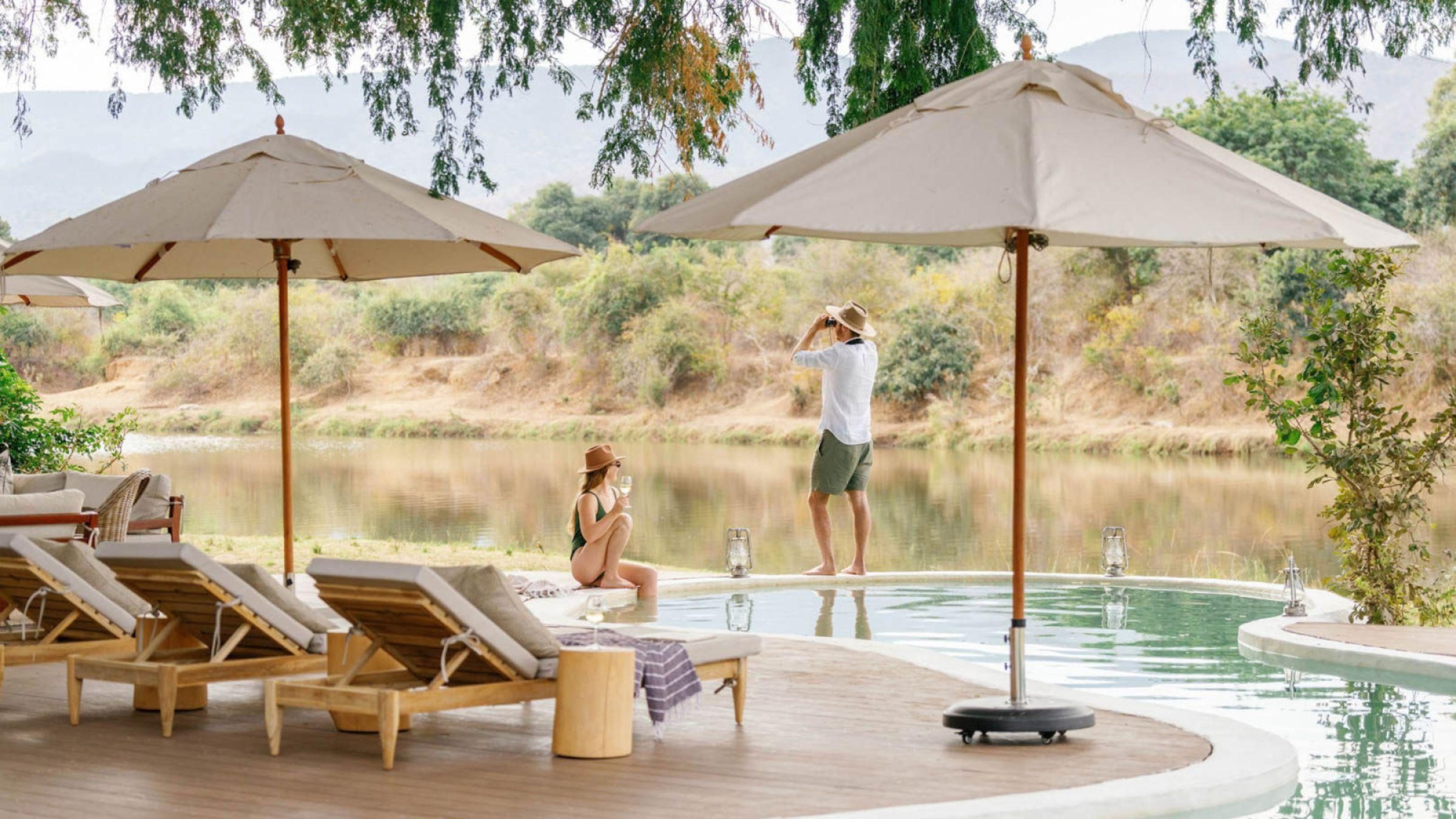 Time Tide Chongwe House - Couple relax beside the pool overlooking the river hero