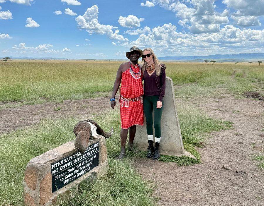 Client stands in Maasai Mara man in traditional dress