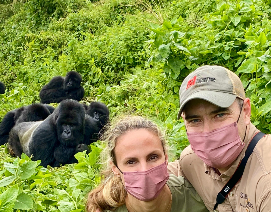 couple pose in front of gorillas in Rwanda
