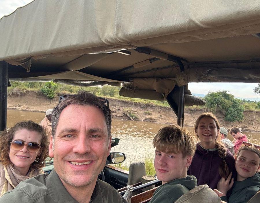 Family pose for photo on safari vehicle