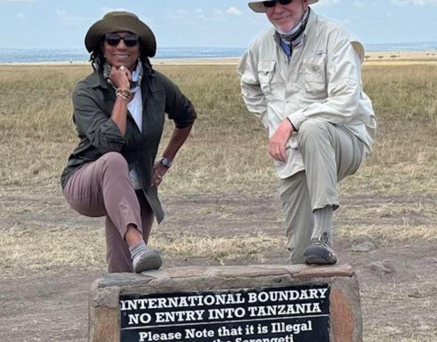 Couple pose on boundary sign of Tanzania