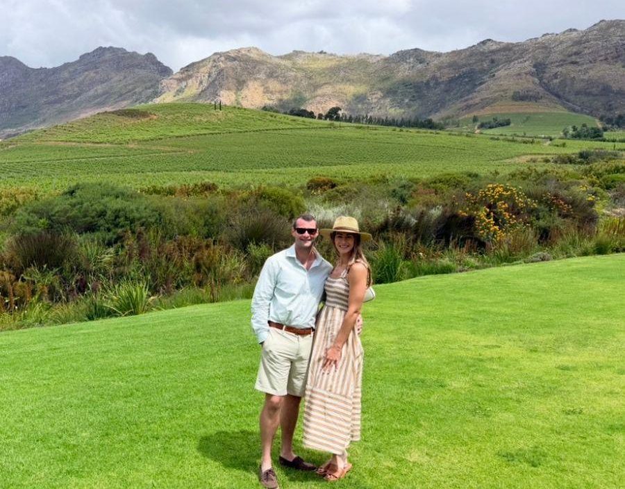 Couple pose for photo on grass of South African wine farm
