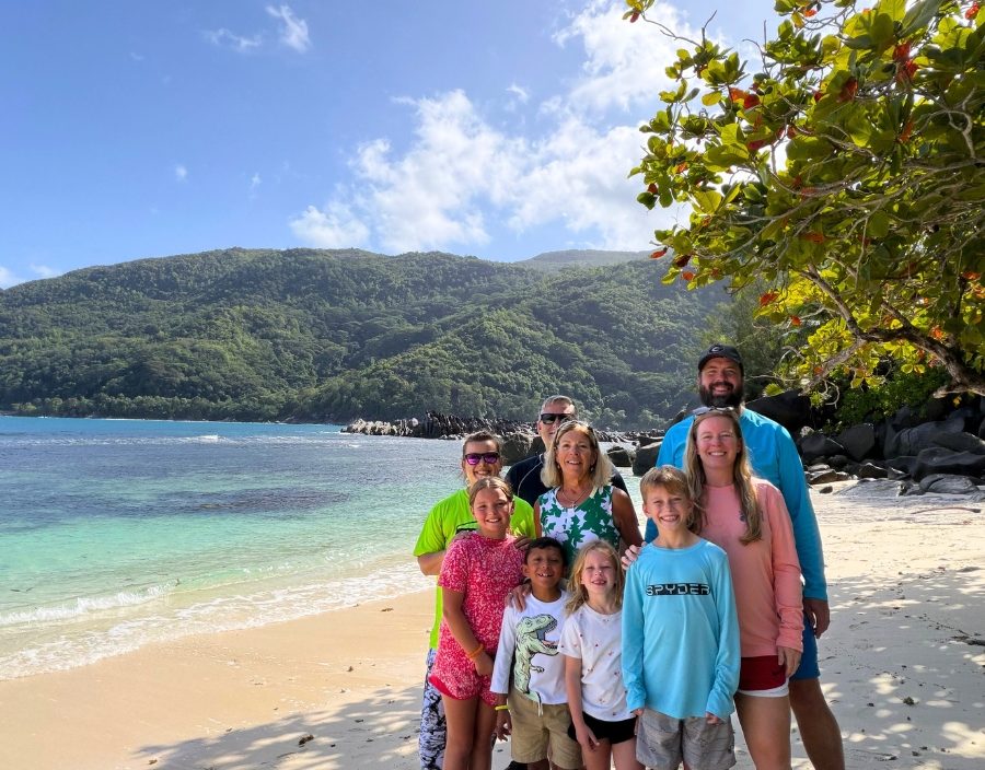 family pose on beach of seychelles