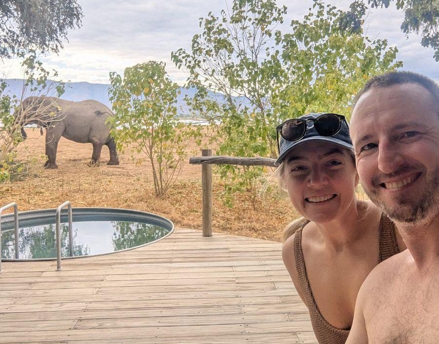 Couple pose in front of private plunge pool while elephant stands in background at Zimbabwe lodge