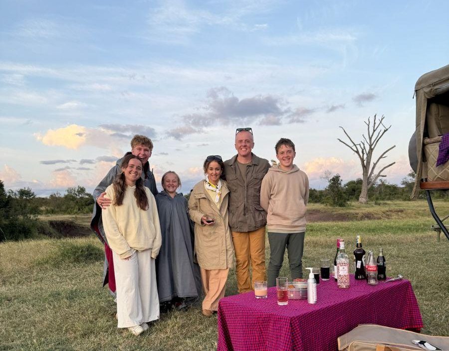 family pose for photo while enjoying a sunset drink stop of safari