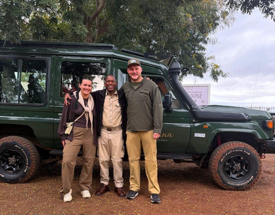 Couple pose in front of safari vehicle
