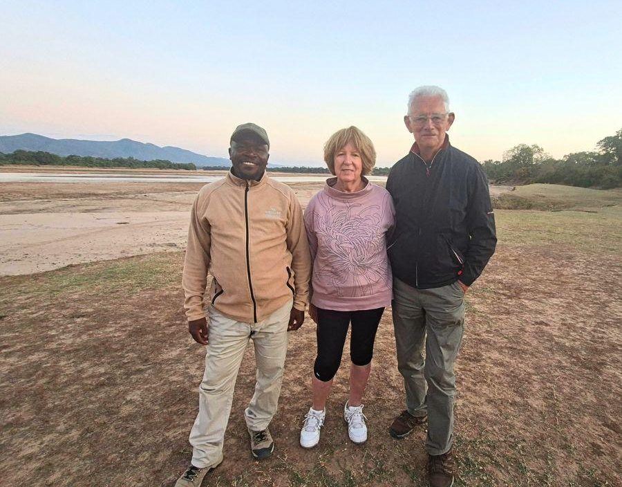 Couple pose with safari guide in Zambia