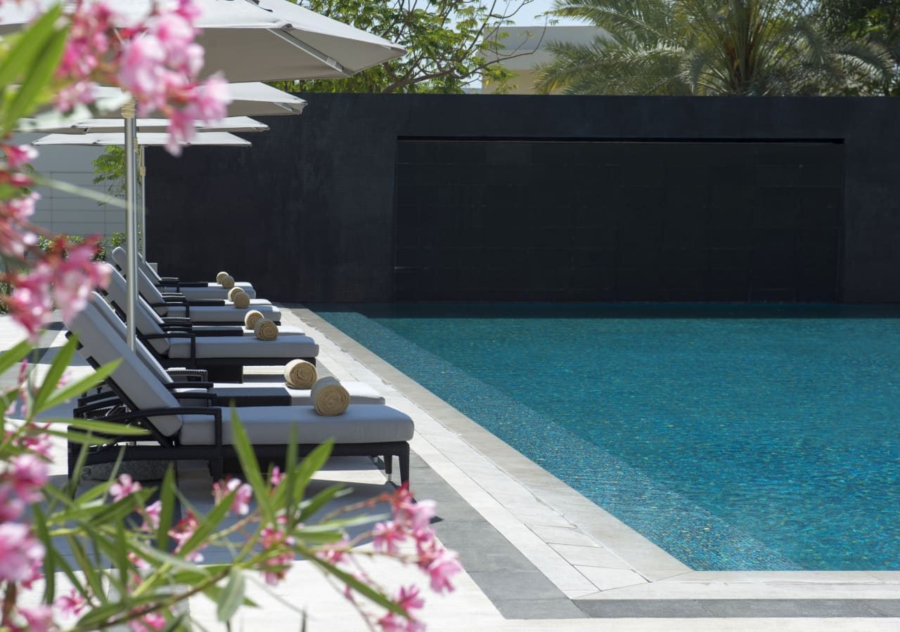 Kempinski hotel muscat sun loungers by the pool 1280