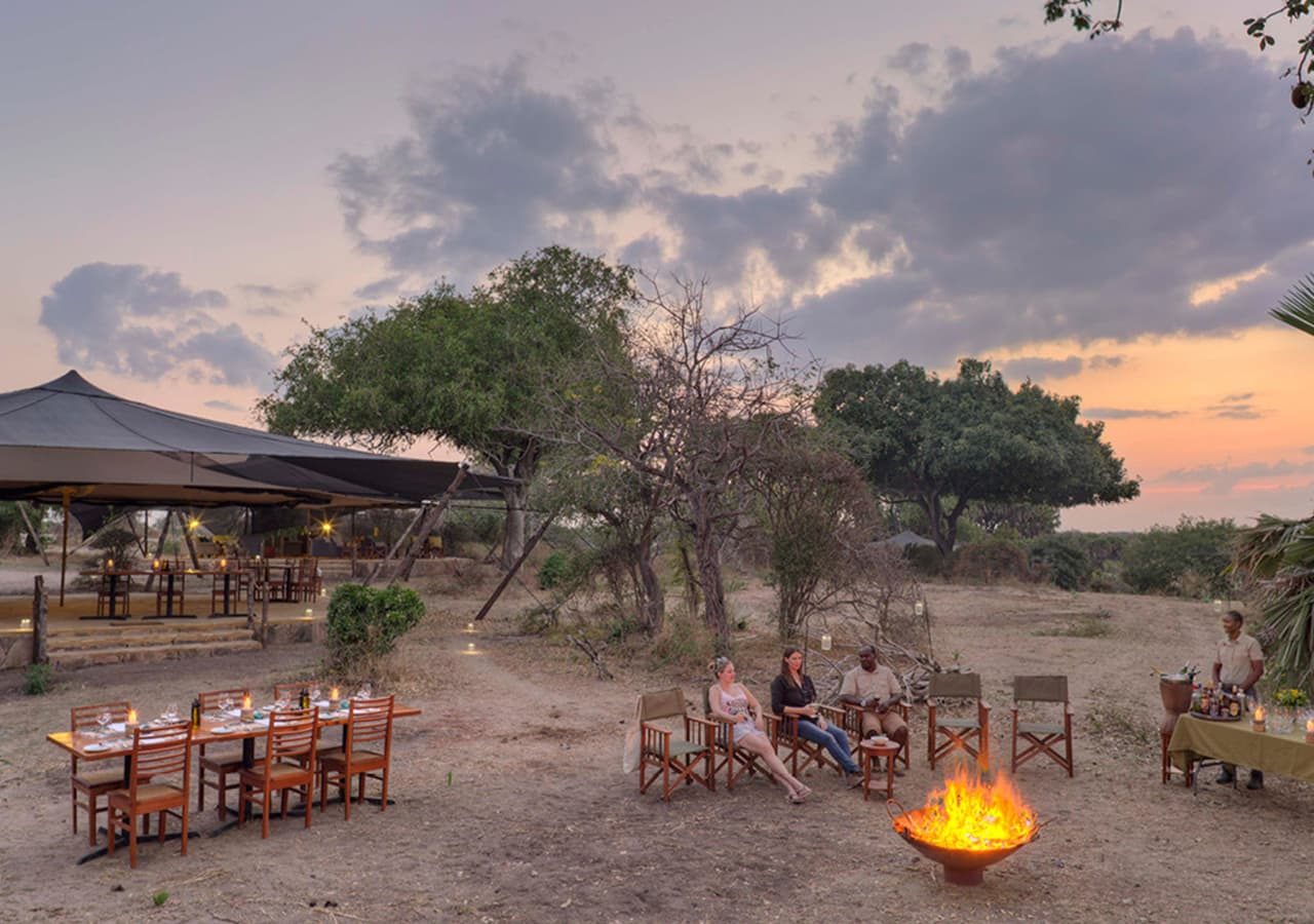 Asilia roho ya selous guests enjoying sundowners by the fire 1280