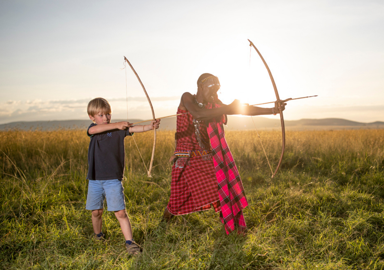 maasai warrior teaching a young boy archery